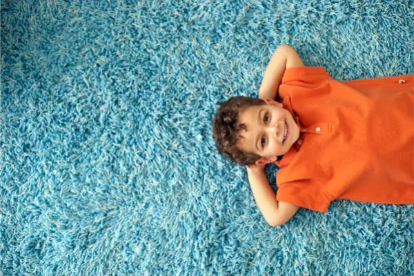 Child lying on a clean carpet after deep cleaning with carpet cleaner shampoo, supporting a fresher and healthier indoor home environment.