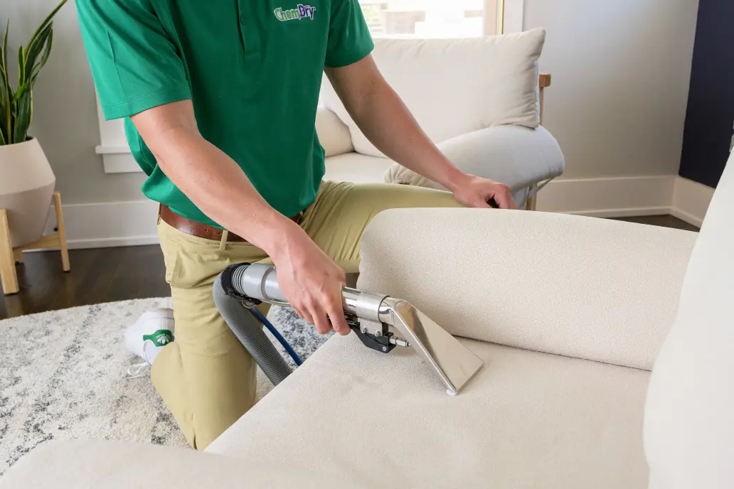 Professional upholstery cleaning service removing dirt and stains from sofa using steam extraction machine