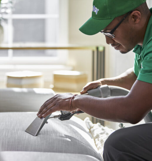Eco Valley Chem-Dry technician performing professional upholstery cleaning on fabric sofa in Calgary home. Upholstery protectant logo representing fabric protection and long-lasting upholstery cleaning results.
