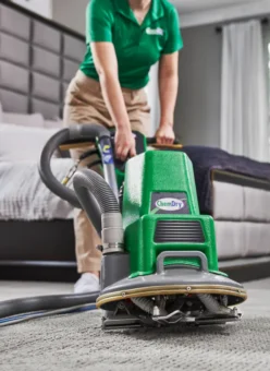 Cleaning services Cochrane technician using low-moisture equipment for deep carpet cleaning in a residential bedroom