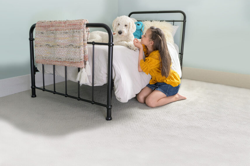 Girl with dog 1 Child playing with a dog in a bedroom with clean carpet flooring, showing a pet-friendly home environment and the importance of effective pet odor removal solutions.