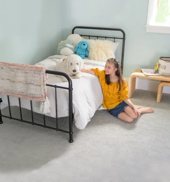 Child sitting beside her dog on a clean bedroom carpet after professional Pet Odor Cleaning Services, creating a fresh and safe home environment