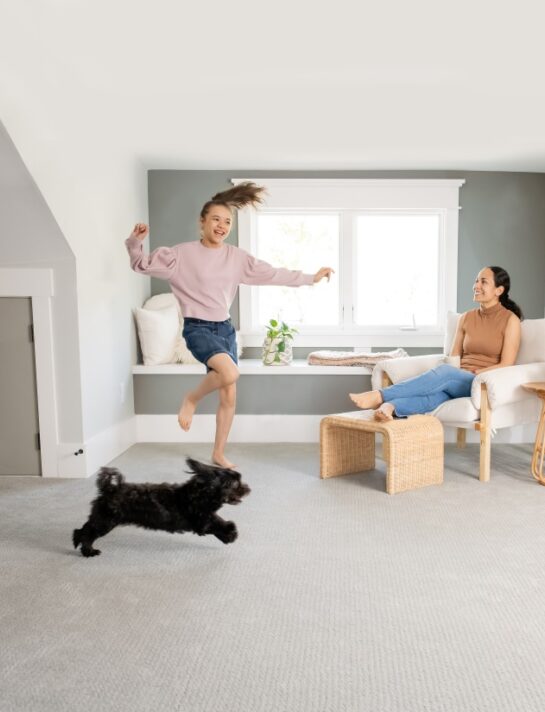 Child playing with a small dog on a freshly cleaned carpet in a Calgary home, showing the comfort and cleanliness delivered by Eco Valley Chem Dry carpet cleaning services. Child playing with her dog on a clean carpet after professional Pet Odor Cleaning Services, creating a fresh and family-friendly home