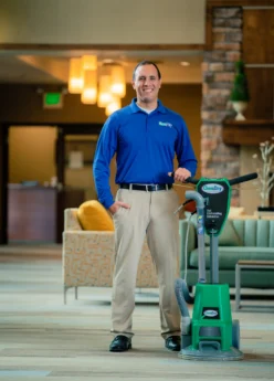 Cleaning services Cochrane professional standing with carpet cleaning equipment, offering carpet and upholstery cleaning services