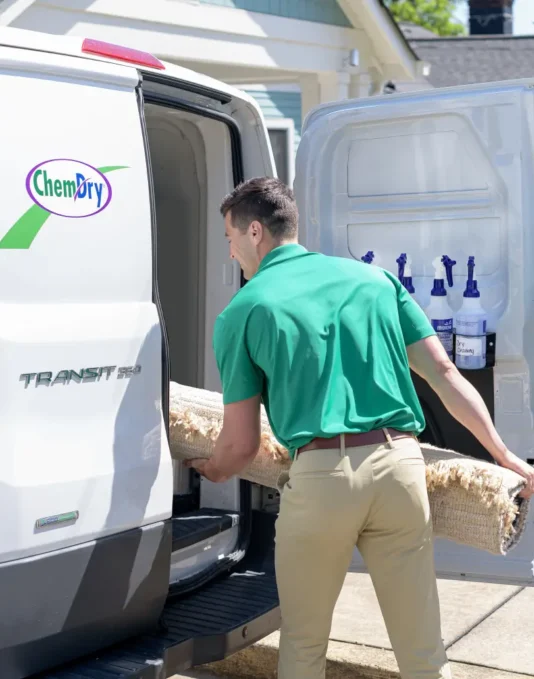 Eco Valley Chem-Dry technician loading carpet into cleaning van in Okotoks