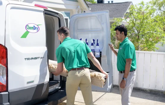 Carpet cleaning technicians unloading equipment and rug from service van in Kensington Calgary
