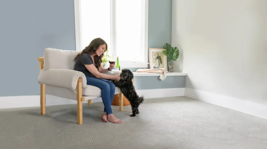 Woman with Dog 3 A homeowner with a dog sitting on a chair in a clean living room with carpet flooring, showing a pet-friendly home environment before professional pet odour removal service.
