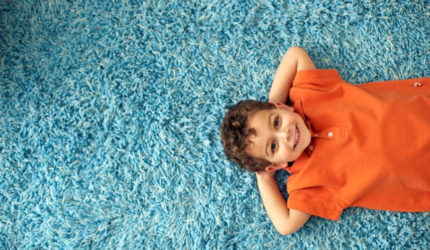Child lying on a clean, fresh carpet after using a pet odor remover for carpet to eliminate stains and dog urine smell