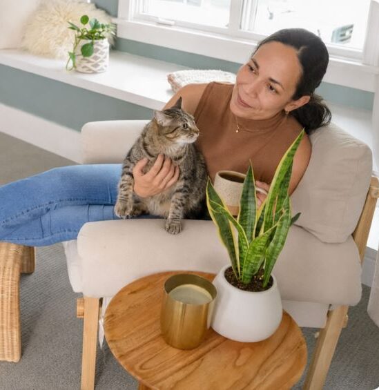 Woman relaxing with her cat in a fresh home after professional treatment kills strong urine smell.
