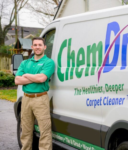 Professional carpet cleaning technician from Eco Valley Chem-Dry standing beside a branded service van in a residential area in Calgary