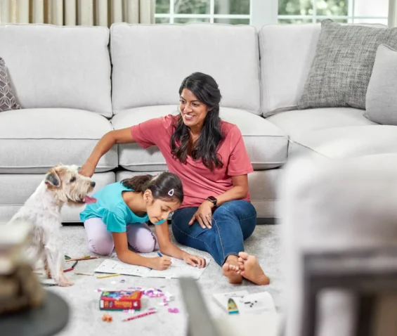 Mother, child, and dog enjoying a clean carpet after professional cleaning removed urine smell.