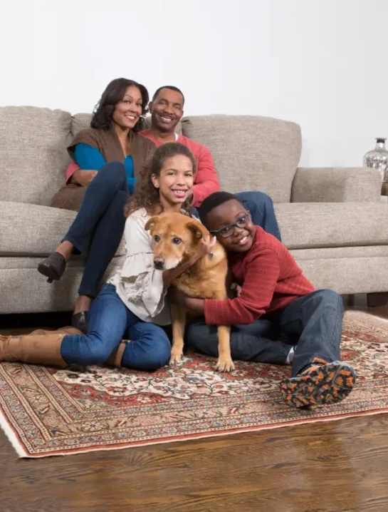 Family relaxing with their dog on a clean carpet after using an enzyme cleaner for dog urine to remove pet stains and odours Happy family relaxing with their dog on a clean rug after professional Pet Odor Cleaning Services, creating a fresh and healthy home environment