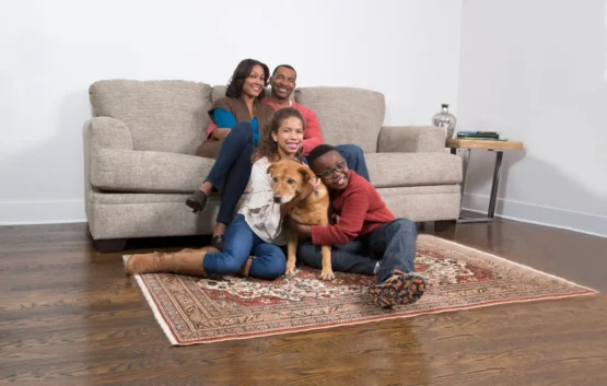 Happy family with a dog sitting on a clean carpet after professional carpet cleaning in Mission Calgary