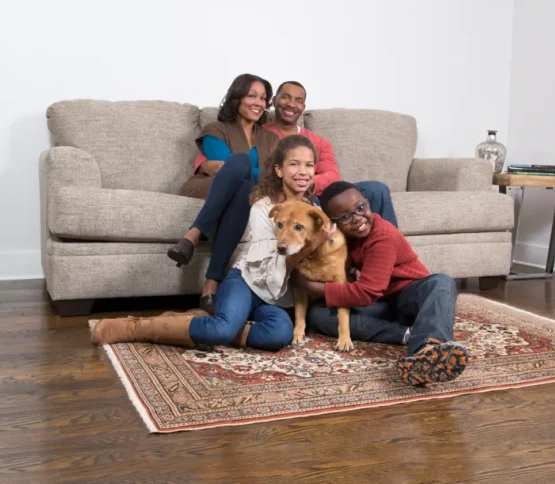 Family relaxing with their dog after carpet cleaning helped get rid of dog urine stains and odors.