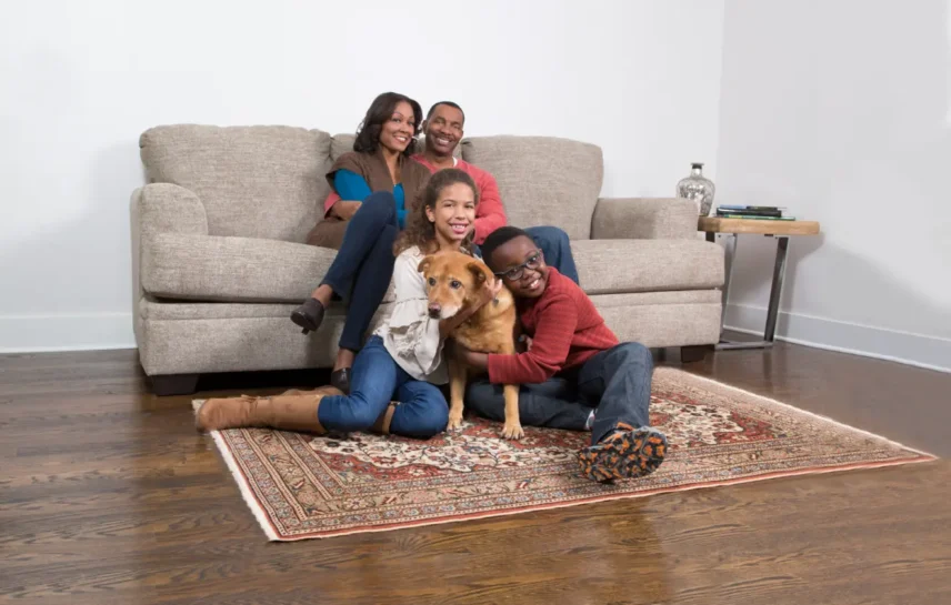 Family relaxing with their dog on a clean carpet after using an enzyme cleaner for dog urine to remove pet stains and odours