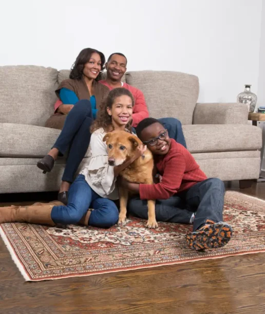family with dog Family relaxing with their dog on a clean rug while asking, “Will carpet cleaning kill fleas?