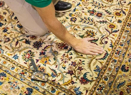 Eco Valley Chem Dry technician inspecting the fibers of a patterned area rug during a professional rug cleaning in Calgary.