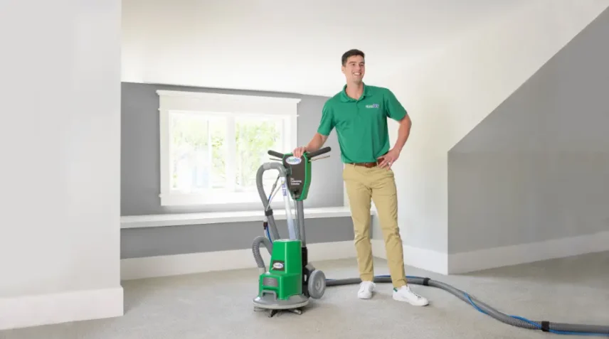 on the spot carpet cleaning specialists 2 Professional carpet cleaner standing next to a Chem-Dry machine on a clean carpet in a bright room.
