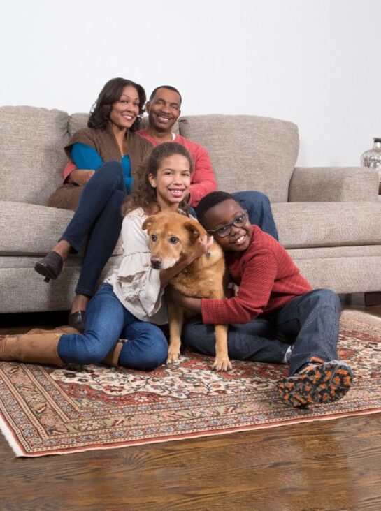 Happy family with their dog relaxing on a clean rug after professional pet urine odour and stain removal service by Eco Valley Chem-Dry in Calgary.
