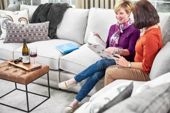 Two women relaxing on a clean sofa after professional upholstery cleaning service in a fresh living room
